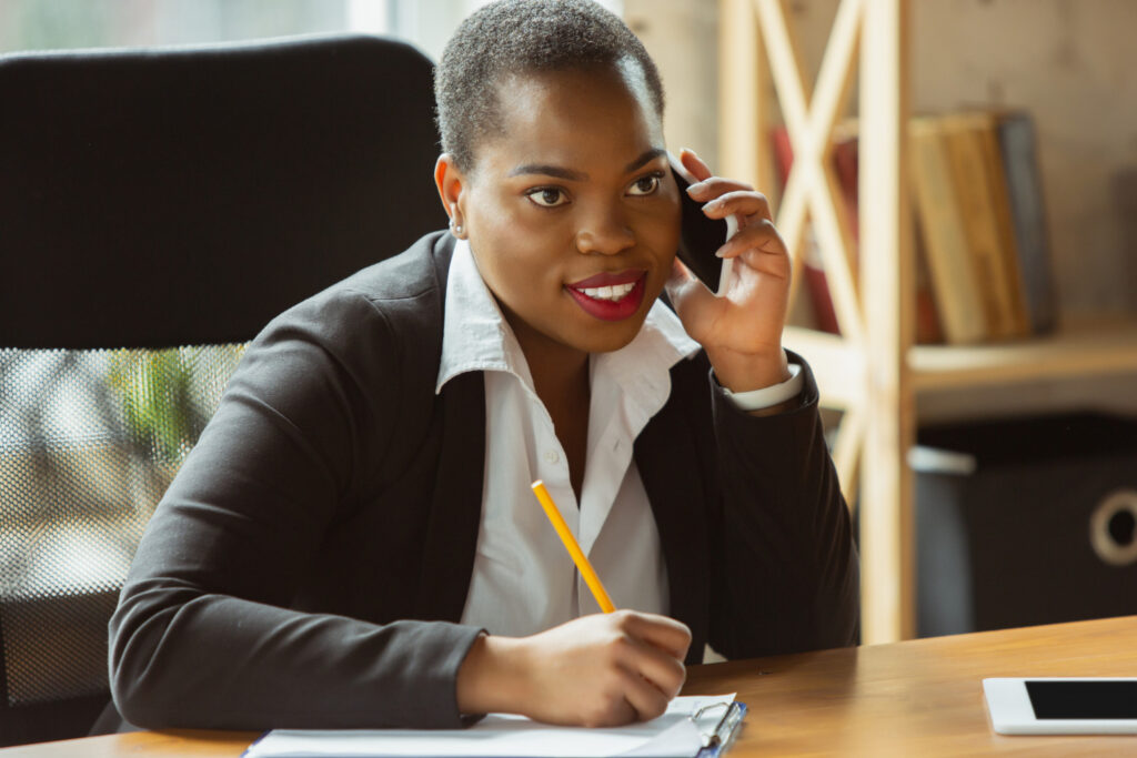 African American businesswoman in office attire smiling, looks confident and happy, busy